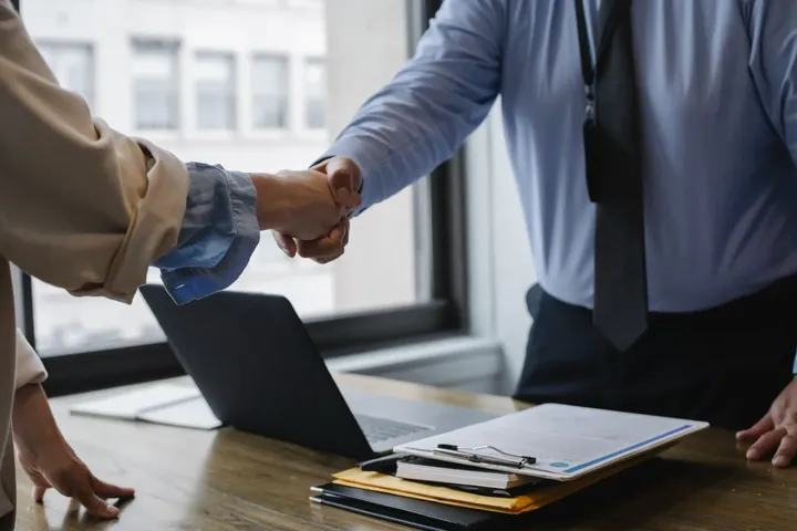 Two people shaking hands in agreement over a desk. Madisonville, Louisiana